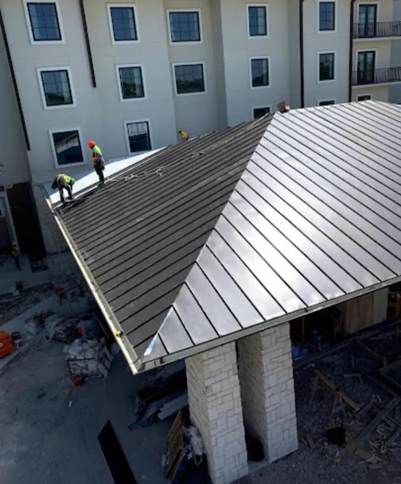 Crew installing standing seam metal roof panels on a commercial project in Tiffin